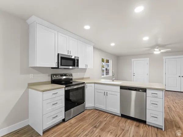 Kitchen featuring stainless steel appliances, a peninsula, light countertops, white cabinets, and recessed lighting