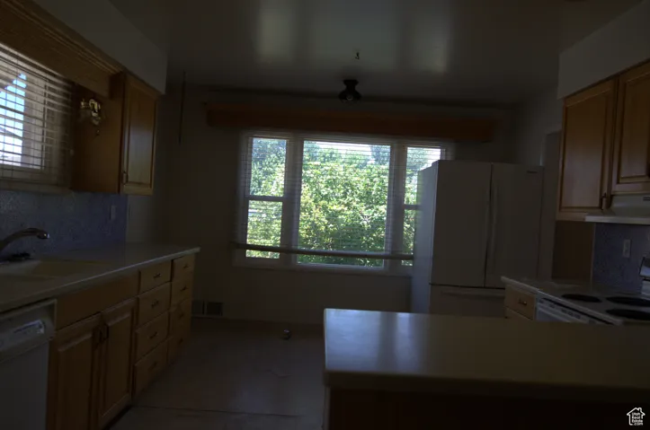 Kitchen featuring decorative backsplash, white appliances, light countertops, and extractor fan