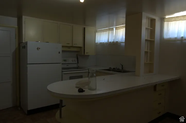 Kitchen with white appliances, plenty of natural light, a peninsula, and white cabinetry