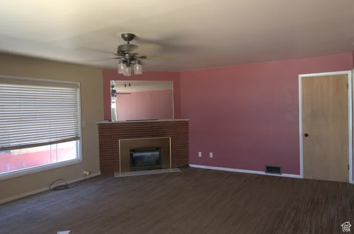 Unfurnished living room with a ceiling fan, a glass covered fireplace, and carpet