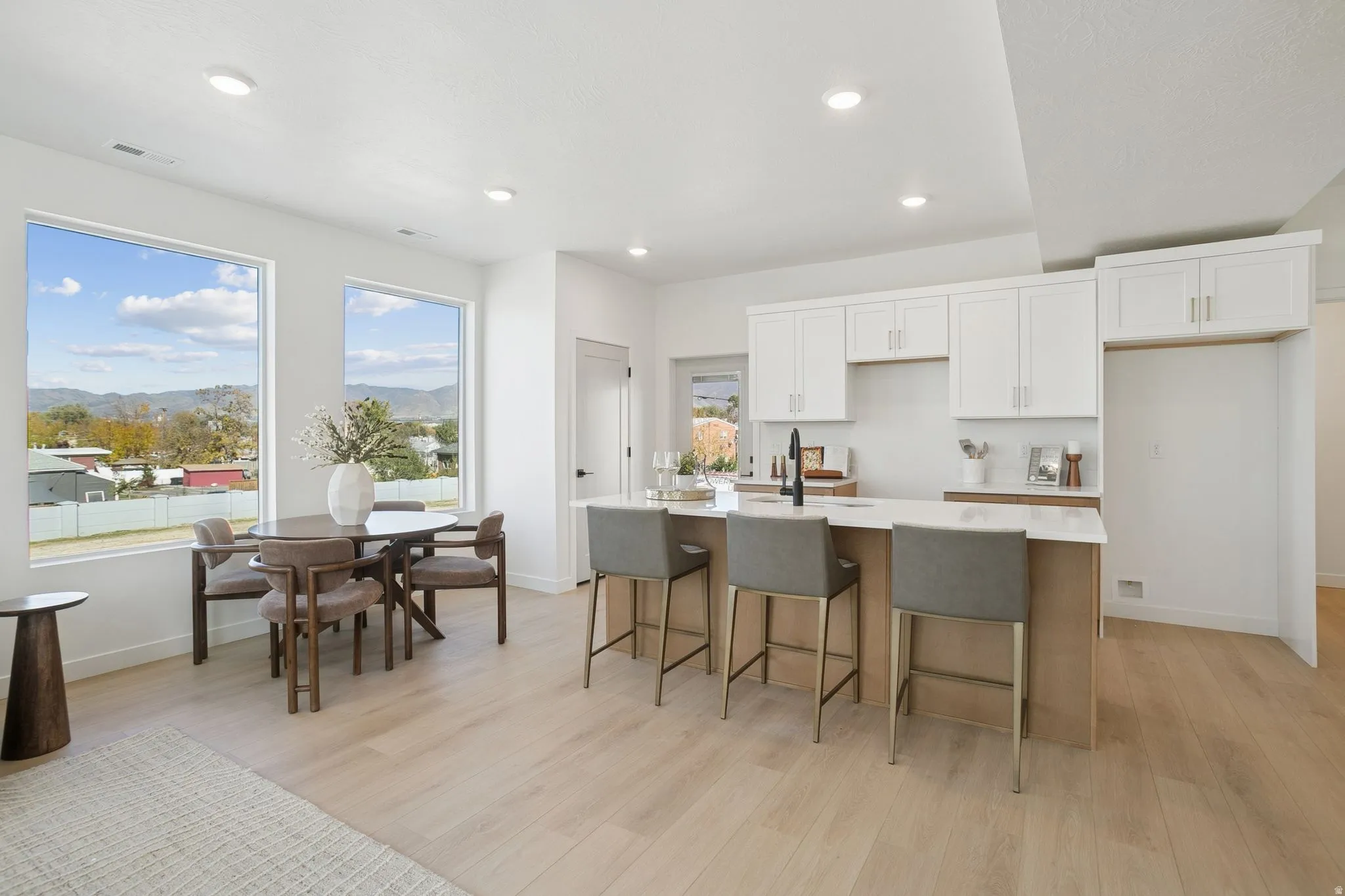 Kitchen with white cabinetry, a center island with sink, light wood-type flooring, recessed lighting, and a kitchen breakfast bar