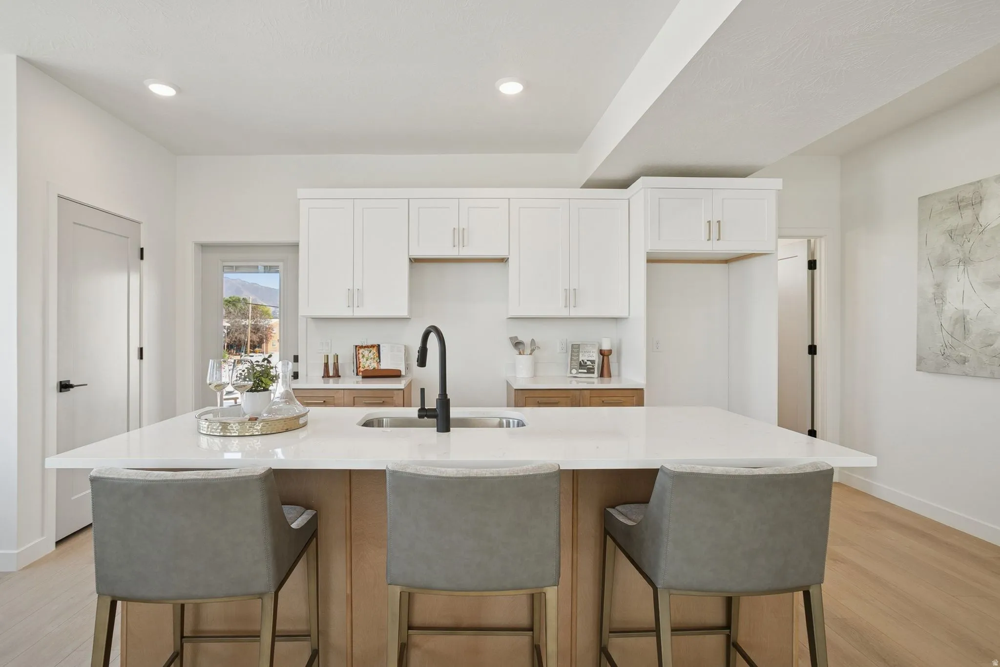 Kitchen featuring white cabinetry, light wood-style floors, a kitchen breakfast bar, light stone counters, and recessed lighting