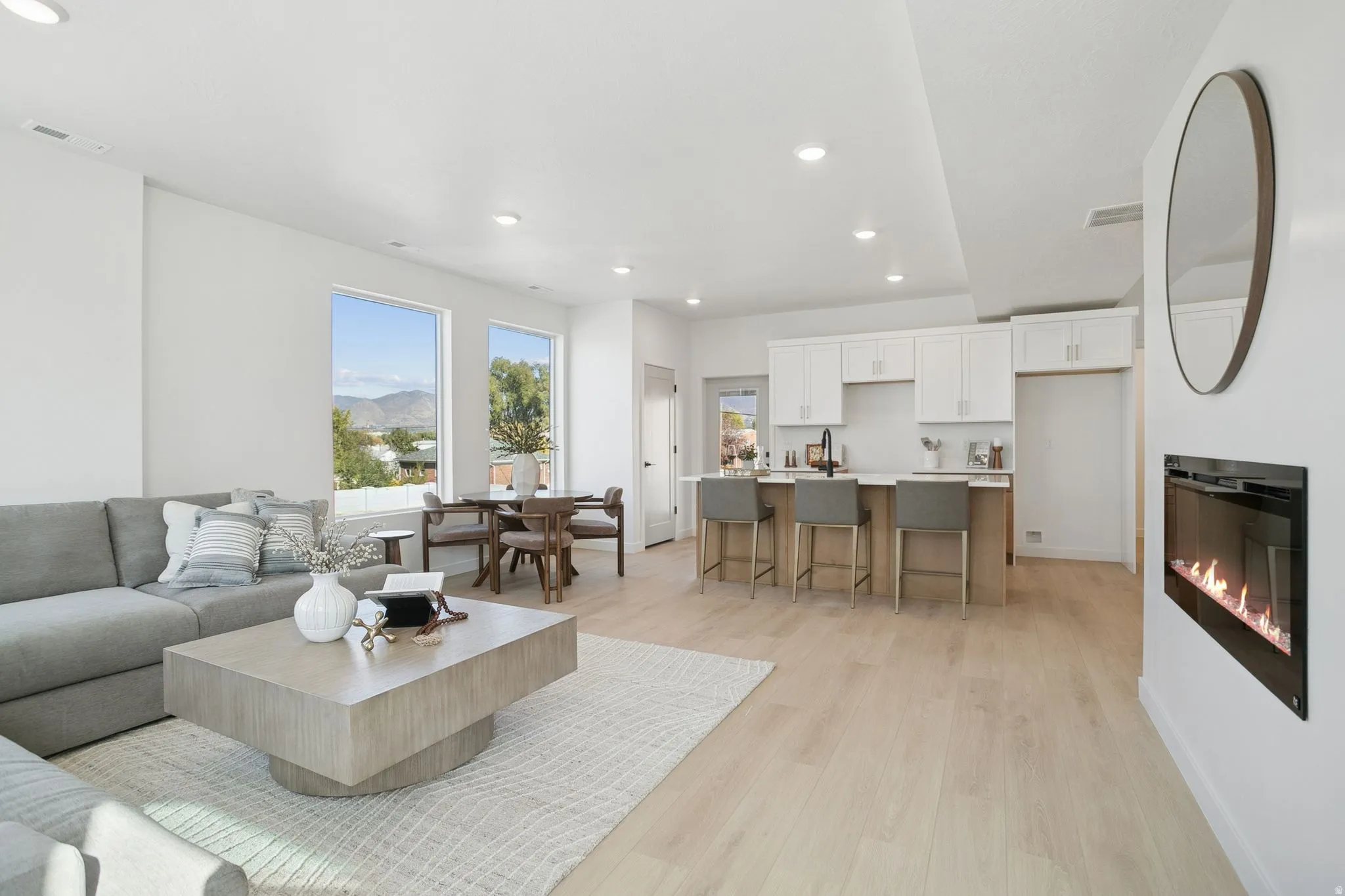 Living area featuring recessed lighting, a glass covered fireplace, and light wood finished floors