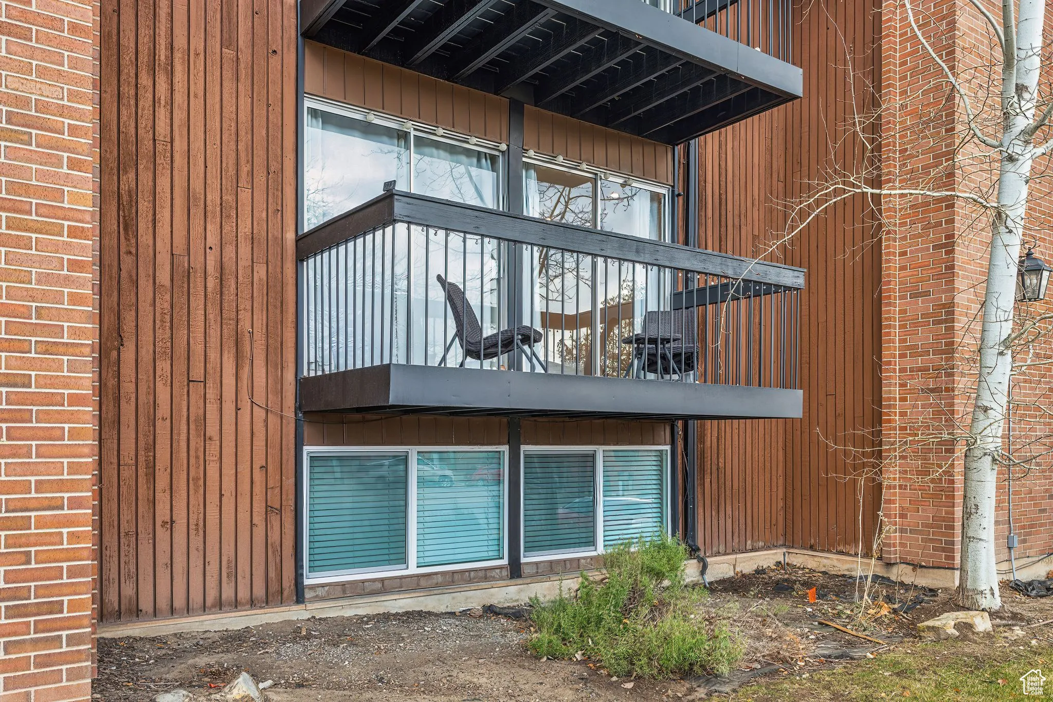 View of property exterior featuring a balcony and brick siding