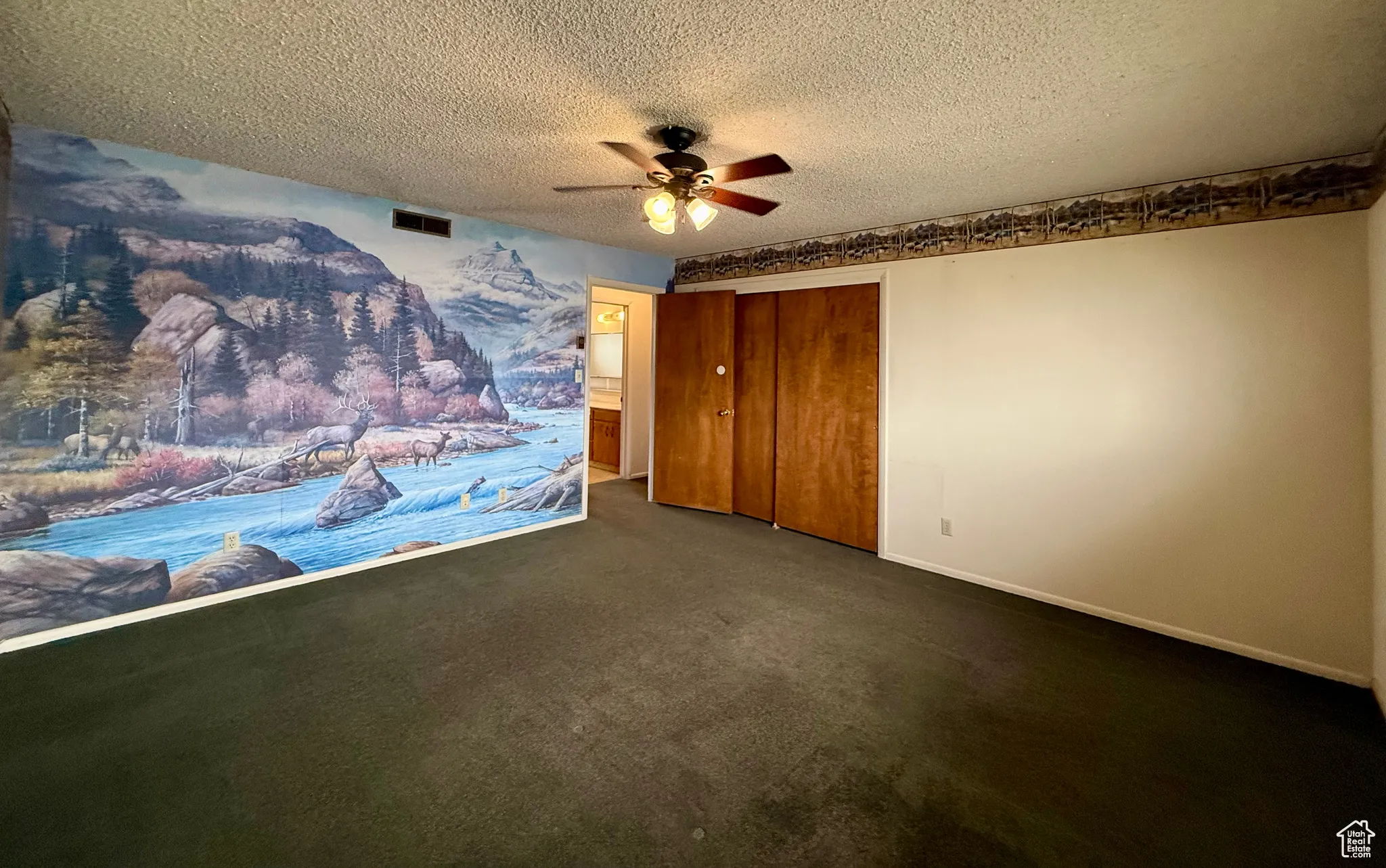 Unfurnished bedroom featuring carpet, a textured ceiling, a closet, and ceiling fan