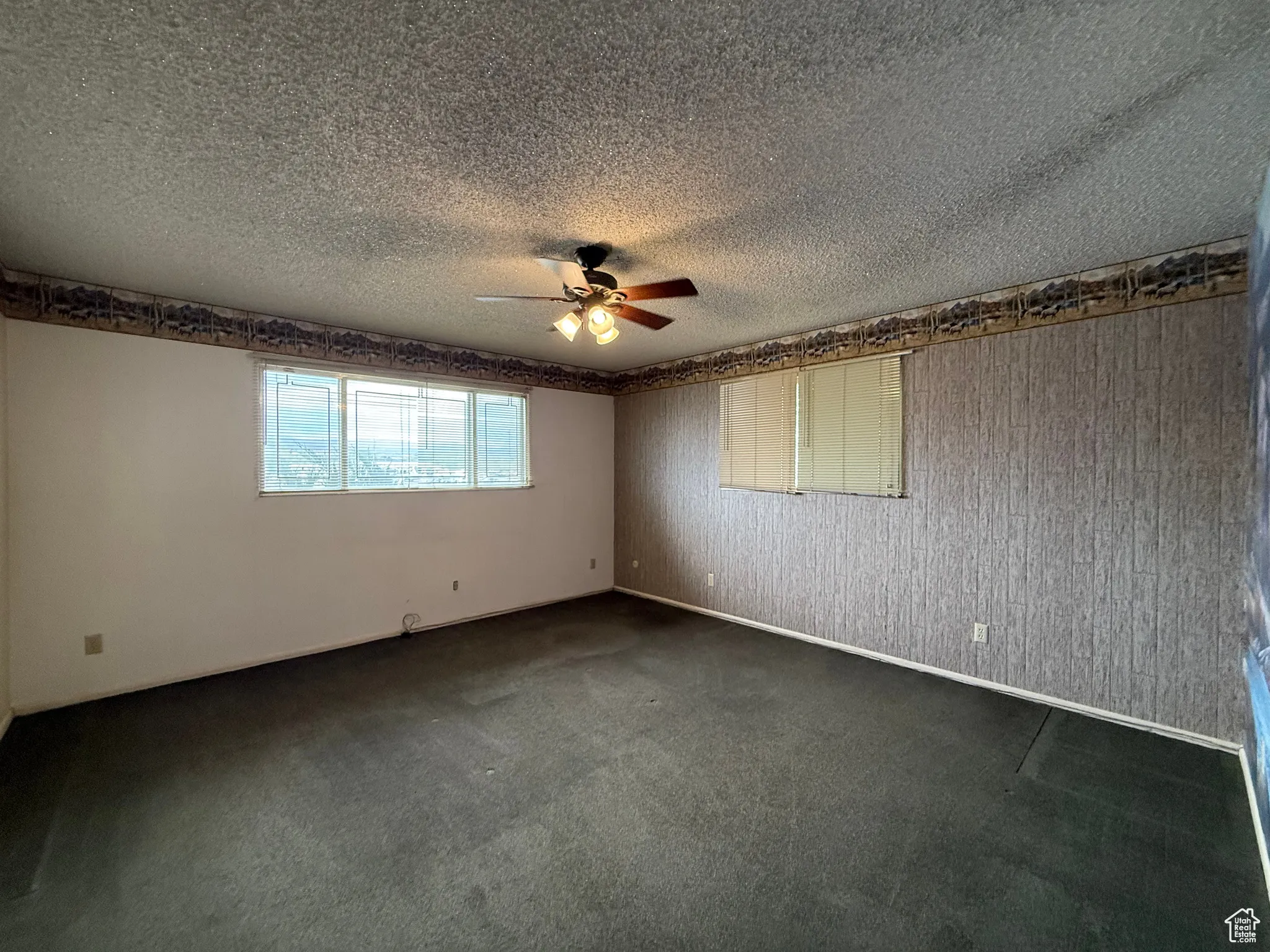 Unfurnished room featuring dark carpet, a textured ceiling, and ceiling fan