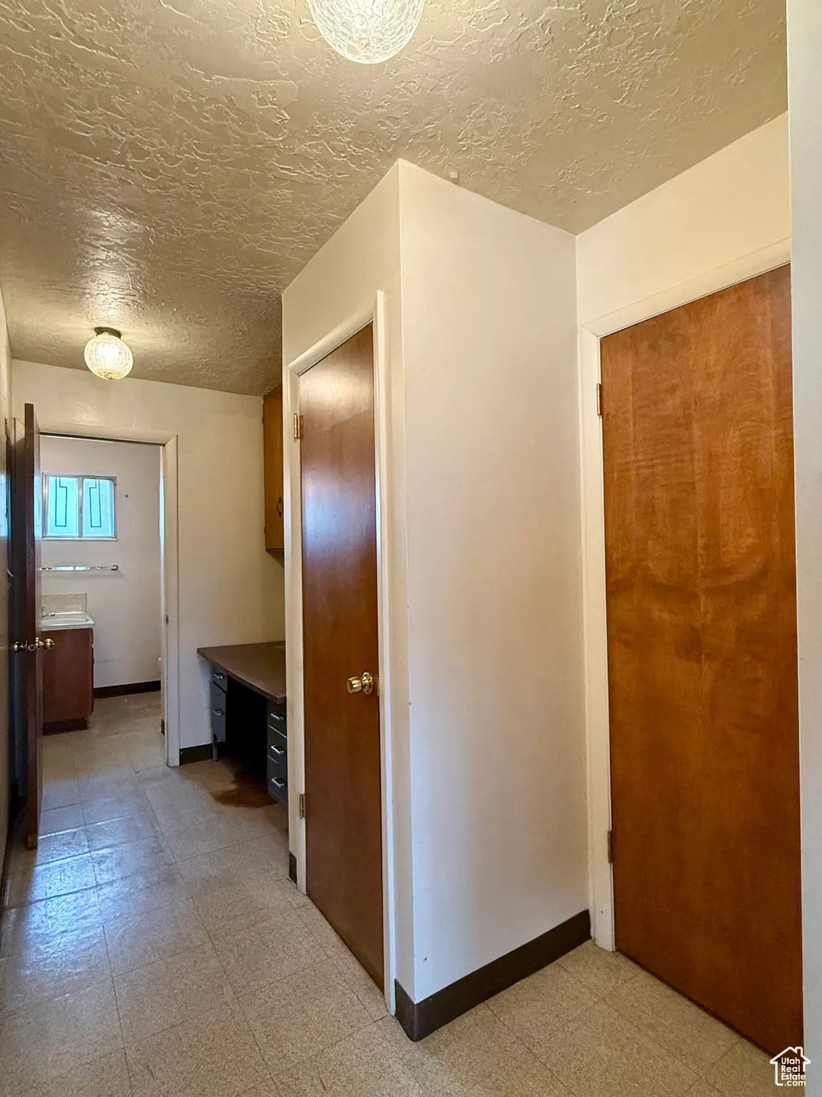 Hall with light flooring and a textured ceiling