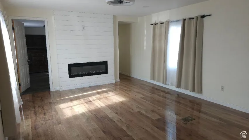 Unfurnished living room with a large fireplace and wood finished floors