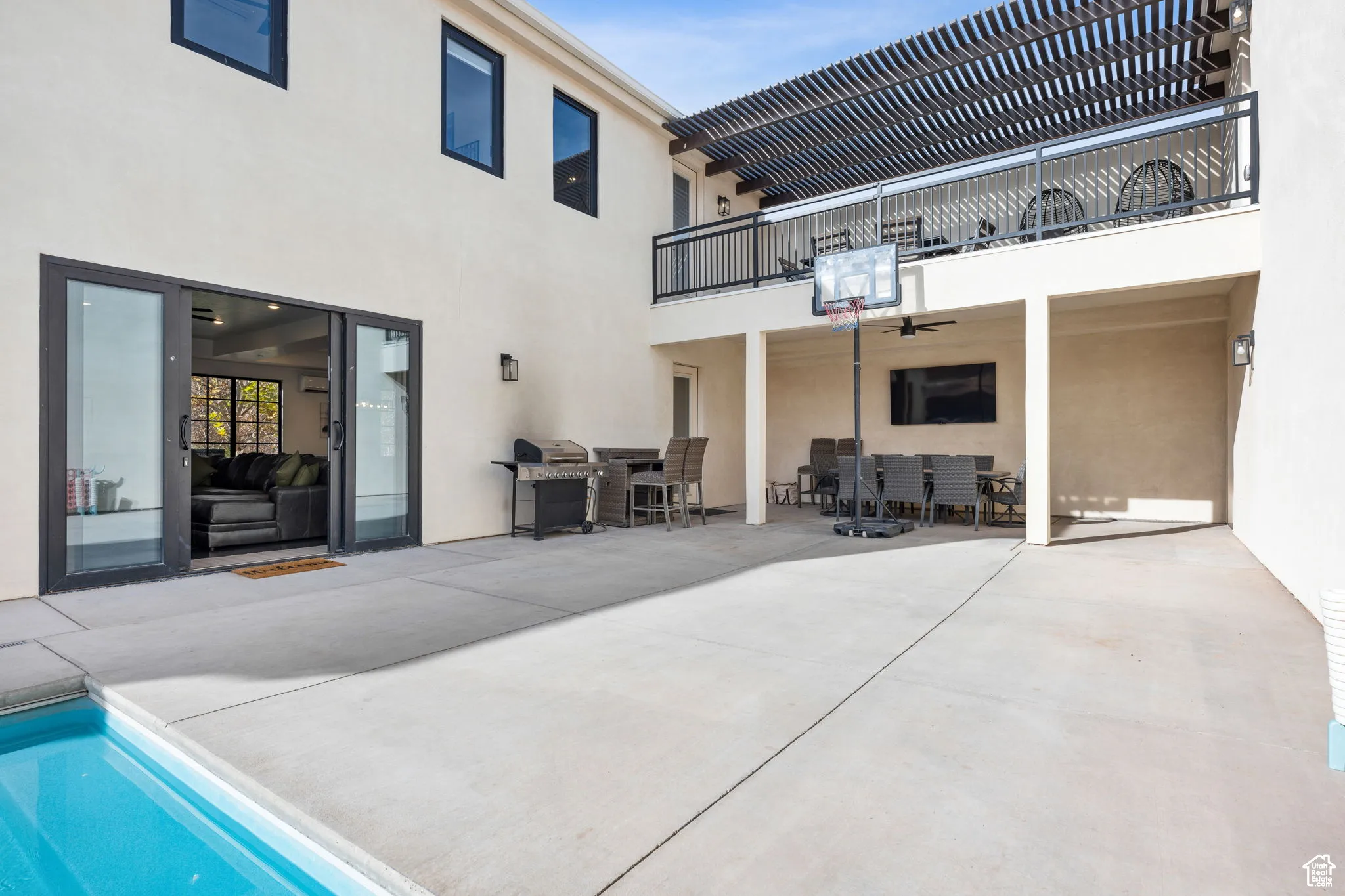 Back of property with a balcony, a patio area, stucco siding, and an outdoor pool