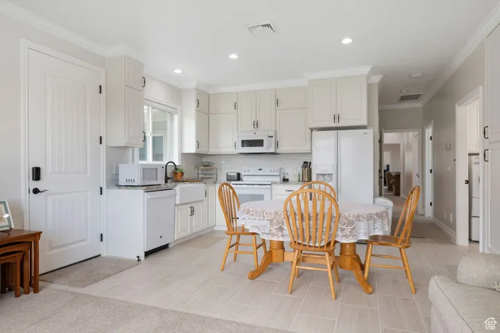ADU Kitchen with ornamental molding, decorative tile backsplash, granite countertops, white appliances, recessed lighting, soft-close cabinetry and tile flooring.