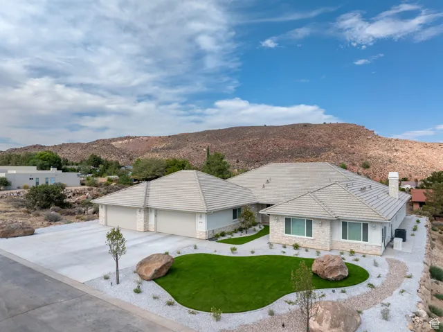View of front of house with stone siding, a mountain view, and stucco siding, Low E Windows, artificial turf