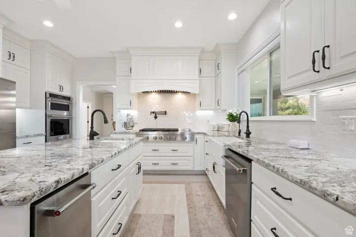 Main Gourmet Kitchen with white soft-close  cabinets, recessed lighting, appliances with stainless steel finishes, granite stone countertops, and decorative tile backsplash