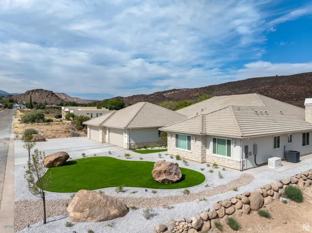 View of front of home featuring stone siding, a mountain view, stucco siding, concrete driveway, and a chimney, Low E Windows