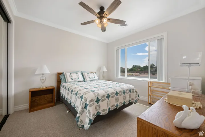 ADU carpeted bedroom featuring crown molding, ceiling fan, and a full length mirrored wardrobe closet