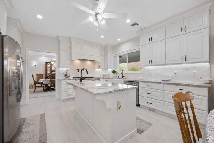 Main Gourmet Kitchen with white tile backsplash, stainless steel appliances, white soft-close cabinets, ceiling fan, granite countertops and recessed lighting with tile flooring