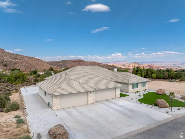 View of front of home featuring stone siding, a mountain view, an attached garage, stucco siding, and driveway, Low E Windows, artificial turf