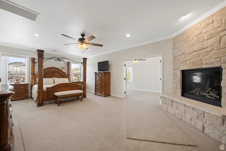 Spacious Master Suite with ornamental molding, floor to ceiling stone fireplace with hearth, ceiling fans in attached office, light colored carpet, recessed lighting.