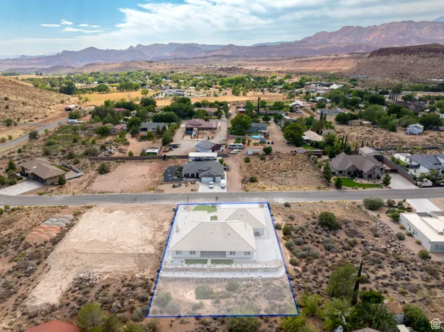 Aerial perspective of suburban area with property parcel outlined and a mountain backdrop