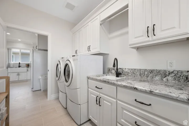 ADU full laundry room with sink, soft-close white cabinetry, recessed lighting and built-in ironing board