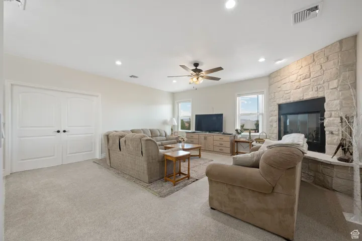Main Family Room area with a fireplace, light colored carpet, recessed lighting, ceiling fan, floor to ceiling wood burning stone fireplace and built in cabinet.  Double doors are to the 5th bedroom / exercise or game room.