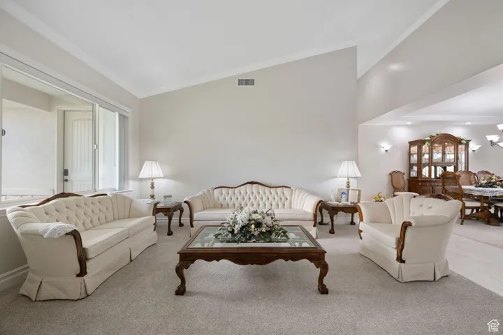 Formal living / dining rooms featuring crown molding, carpet & tile flooring, and high vaulted ceiling, three-tone paint, vaulted ceilings and recessed lighting