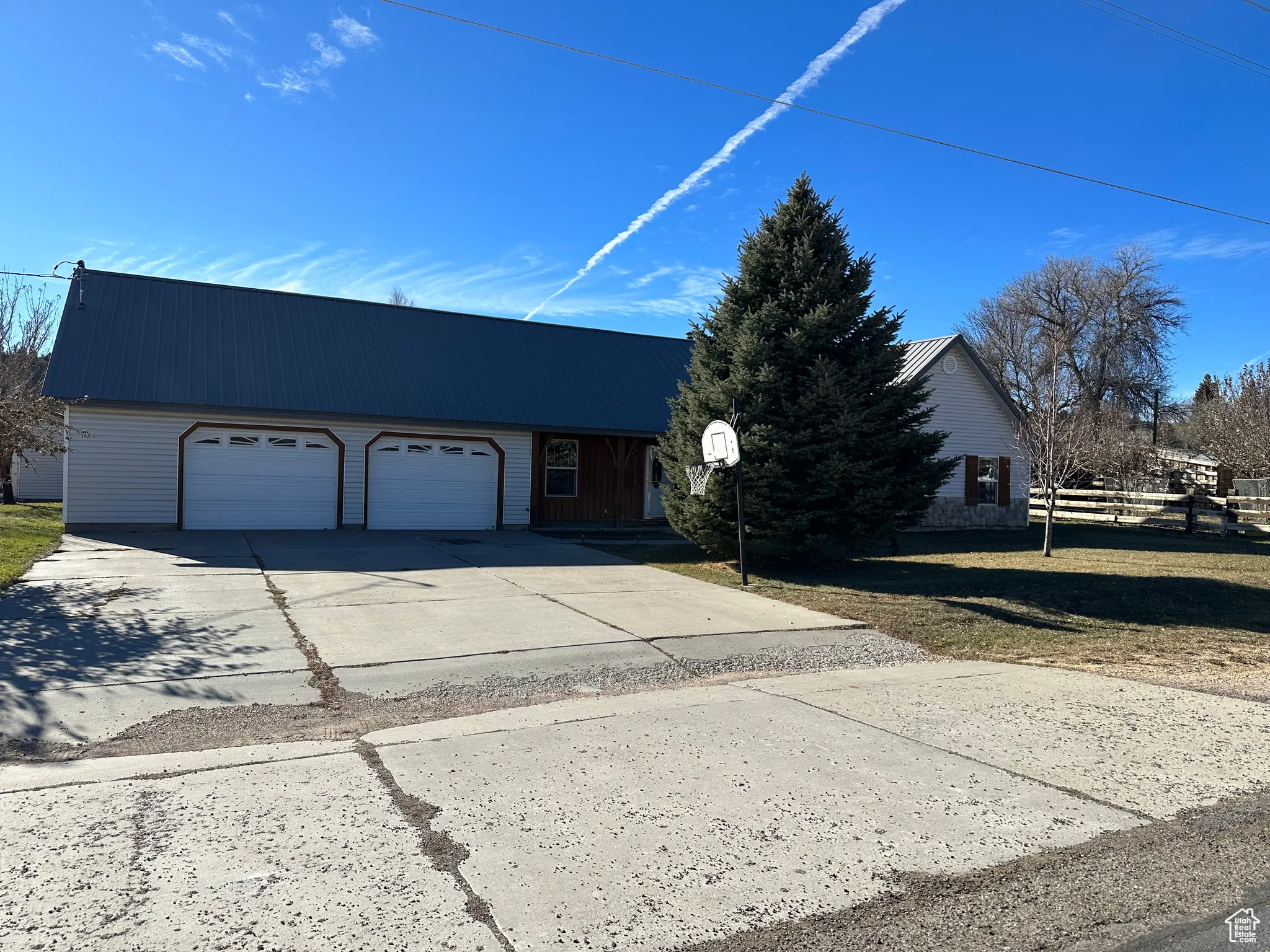 View of front of property with concrete driveway, a garage, and a metal roof