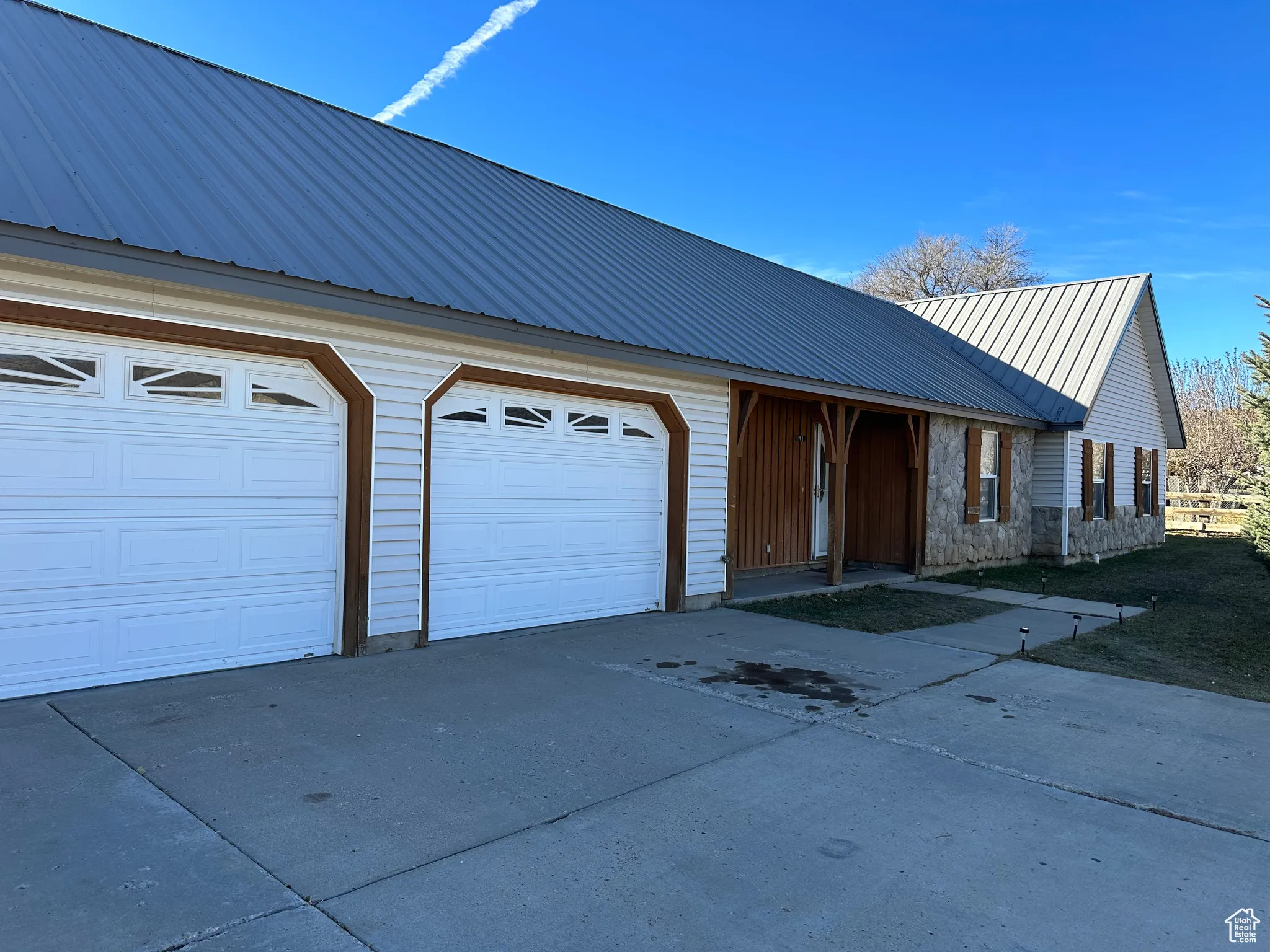 View of front of house with driveway, a metal roof, and an attached garage