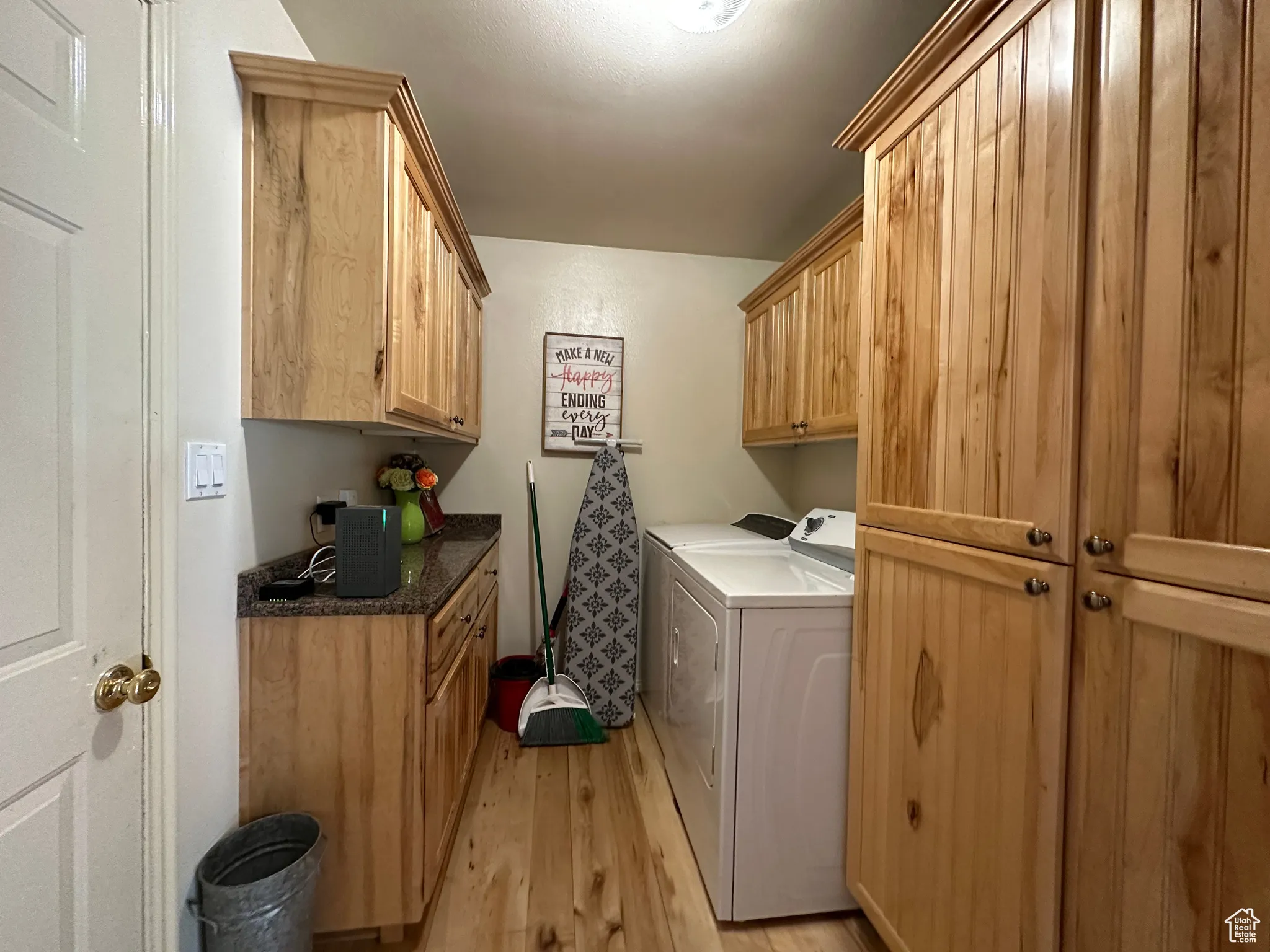 Laundry area with cabinet space, independent washer and dryer, and light wood-style flooring