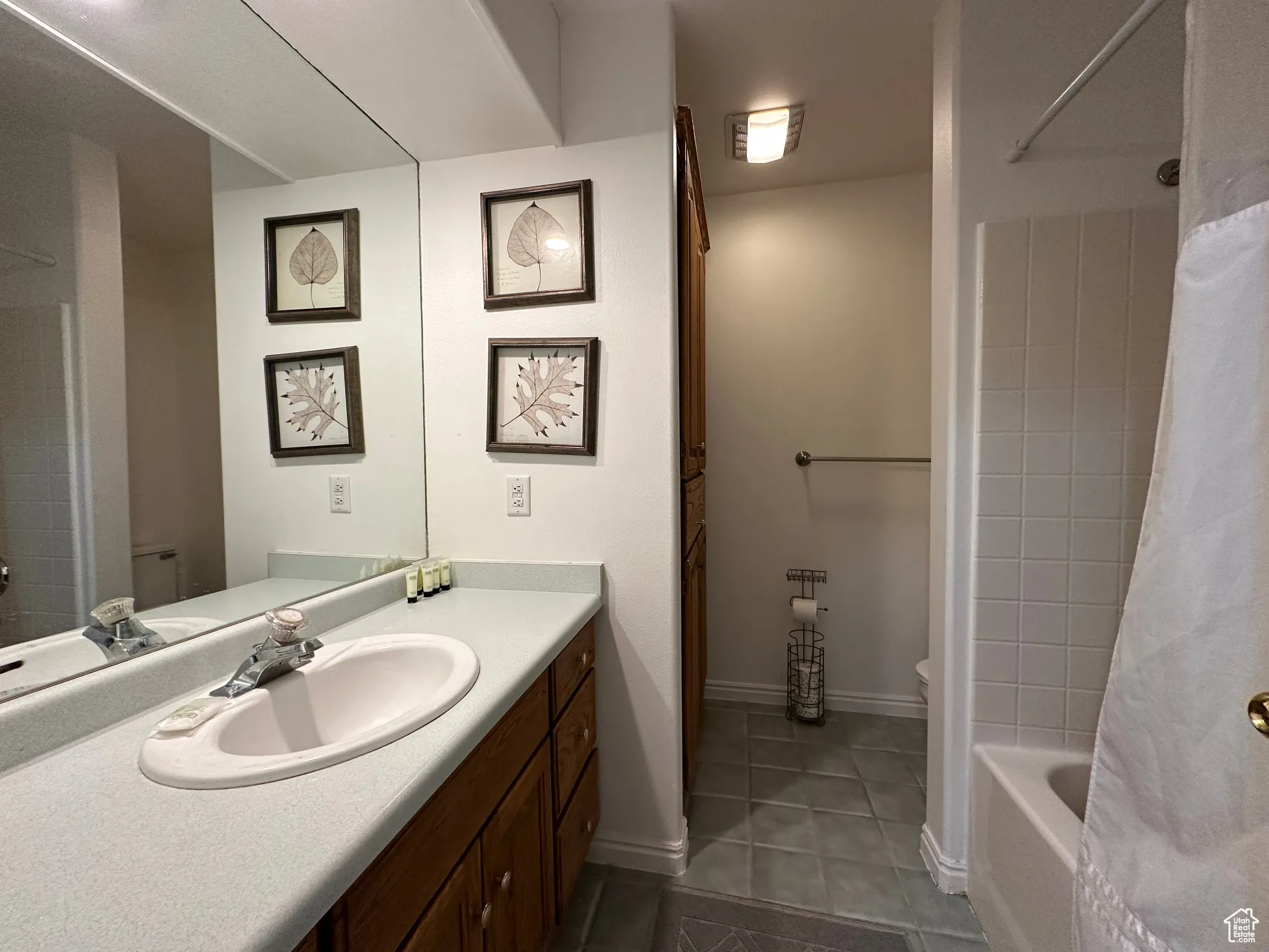 Full bath with tile patterned floors, vanity, and shower / tub combo with curtain