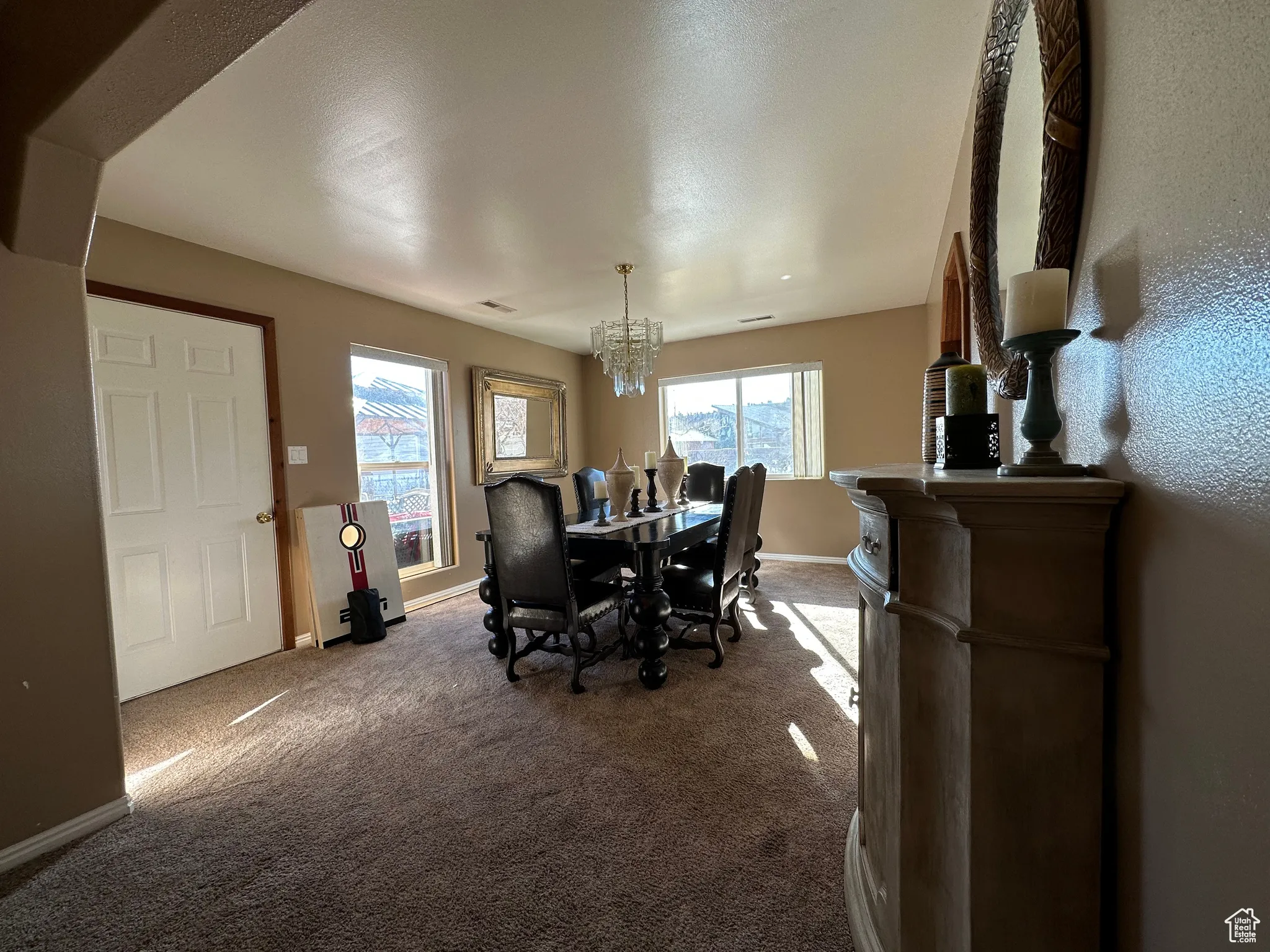 Dining area with carpet, healthy amount of natural light, and a chandelier