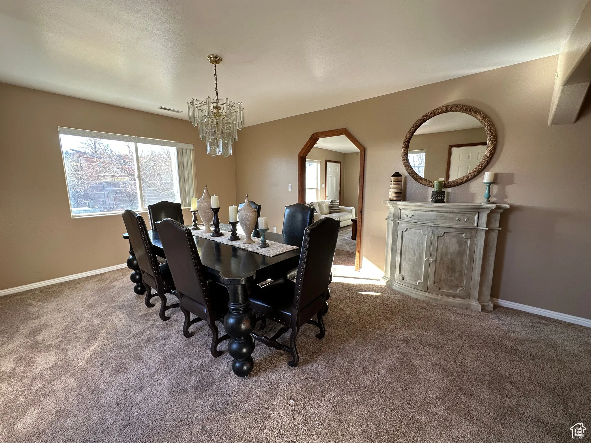Dining area featuring carpet floors, a chandelier, and arched walkways