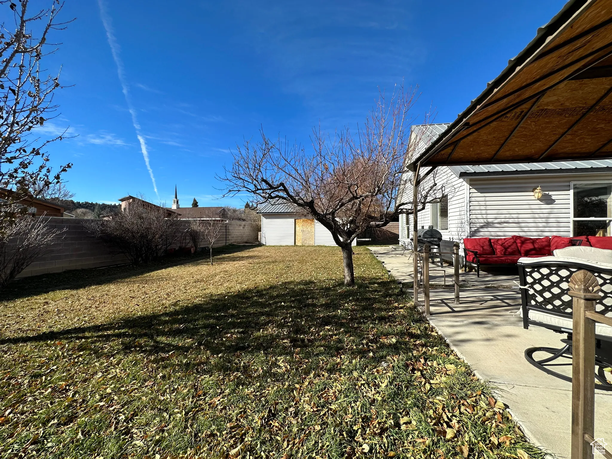 Fenced backyard with a patio area, an outbuilding, and an outdoor hangout area