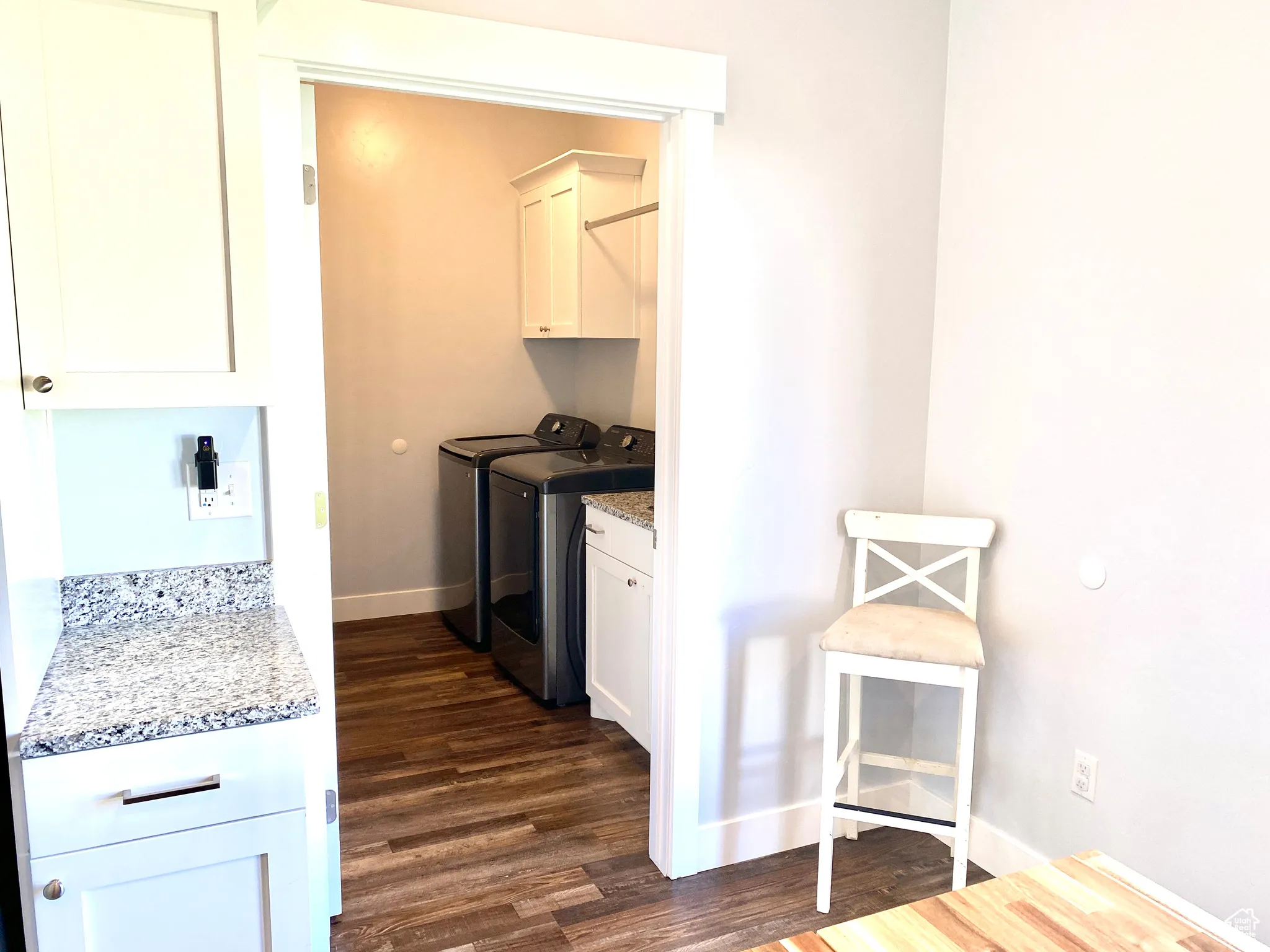 Laundry room featuring cabinet space, washing machine and clothes dryer, and dark wood-style flooring