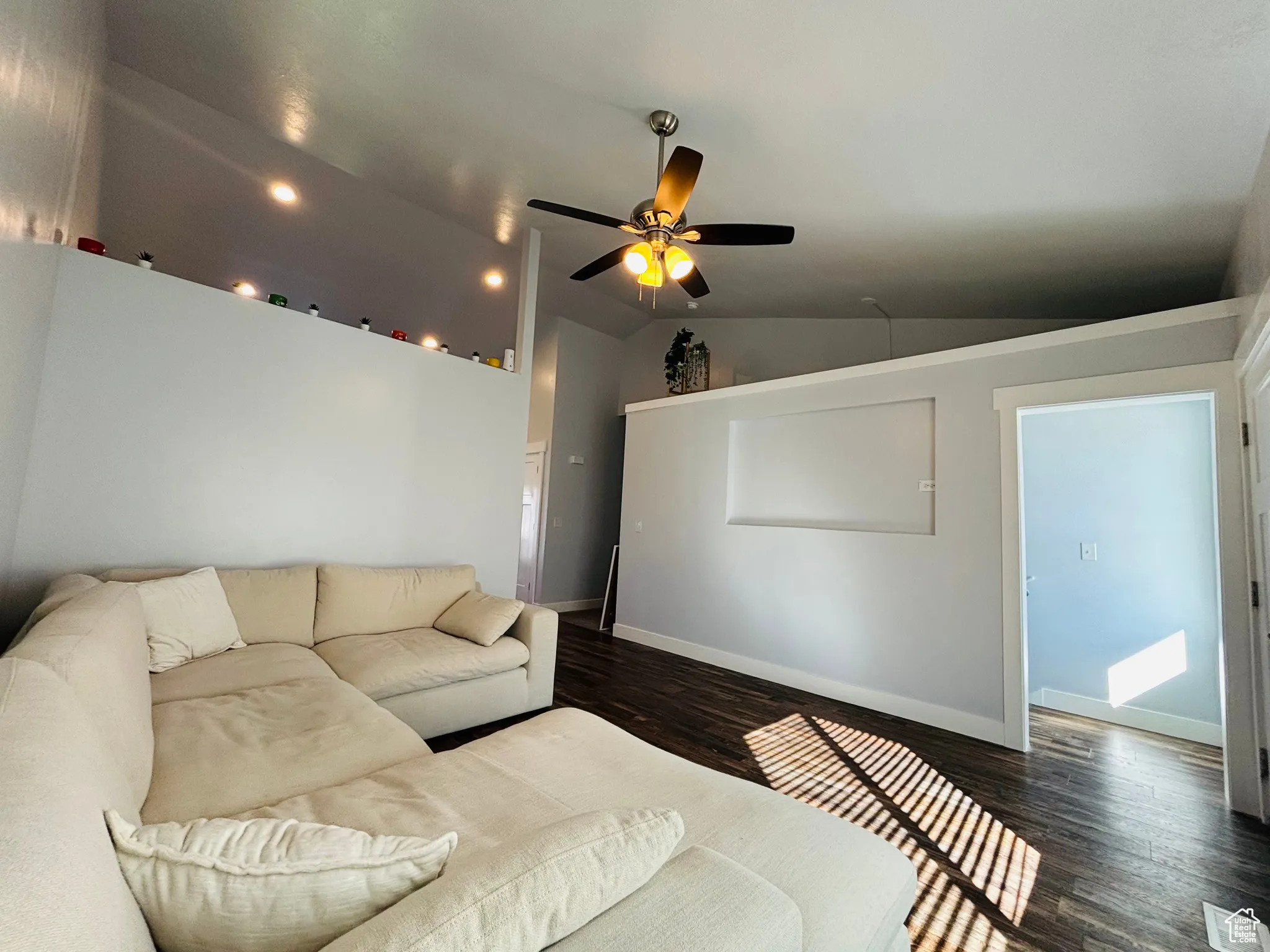 Living room featuring lofted ceiling, wood finished floors, and ceiling fan