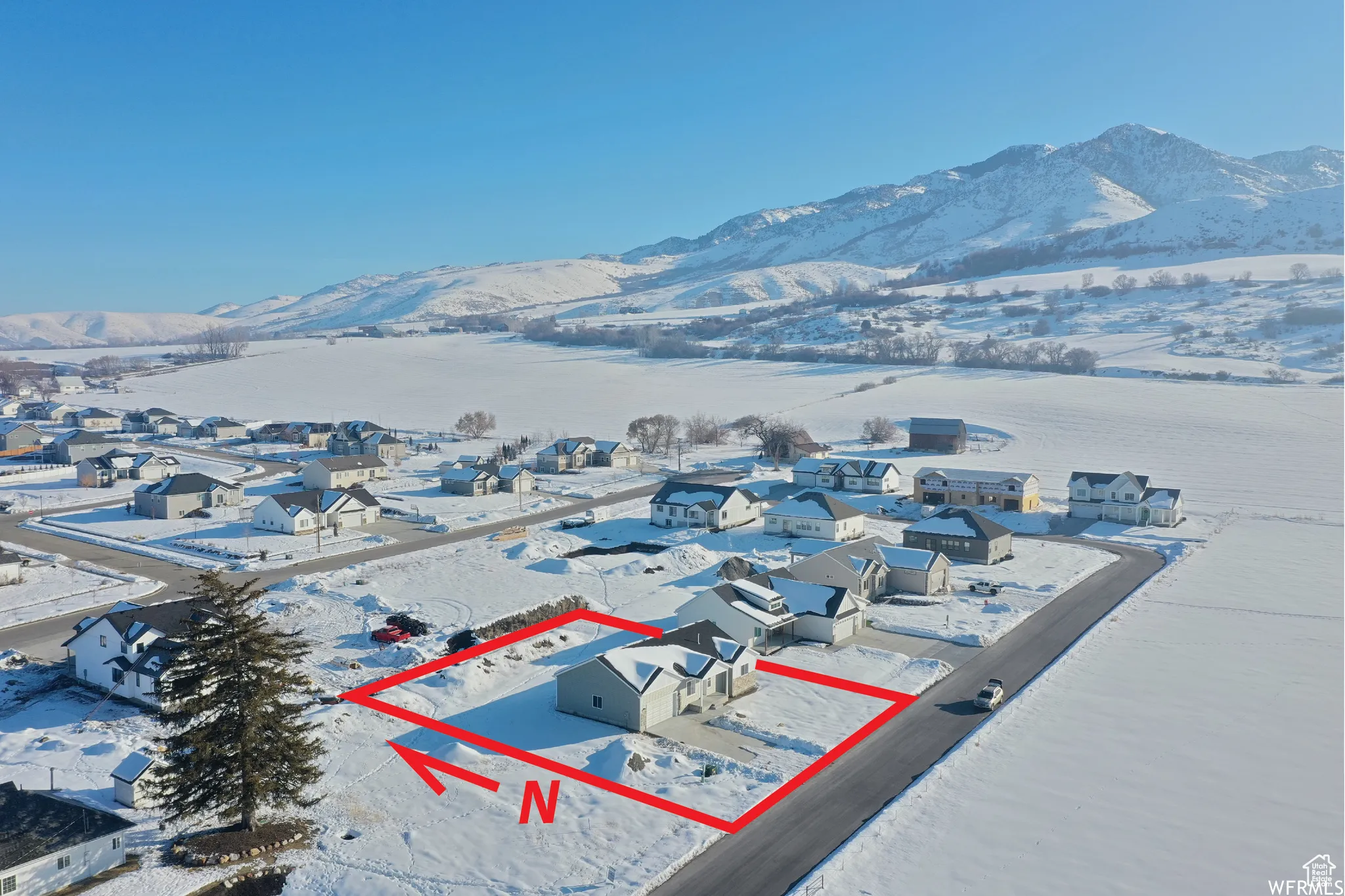 Snowy aerial view with property parcel outlined, a mountain view, and a residential view
