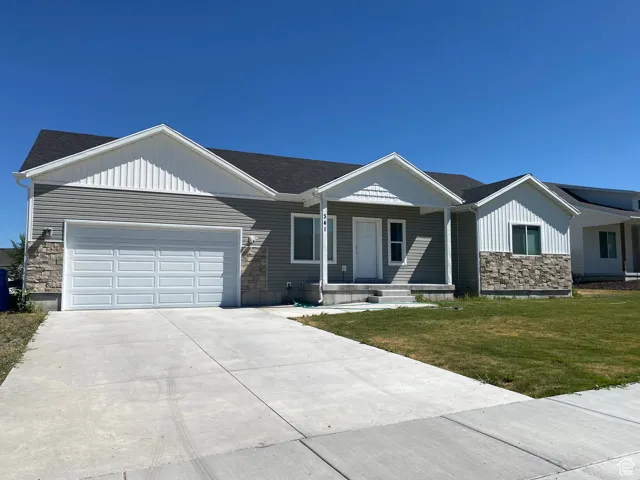 Single story home with stone siding, an attached garage, the front lawn, concrete driveway, and vinyl siding with stone accents.