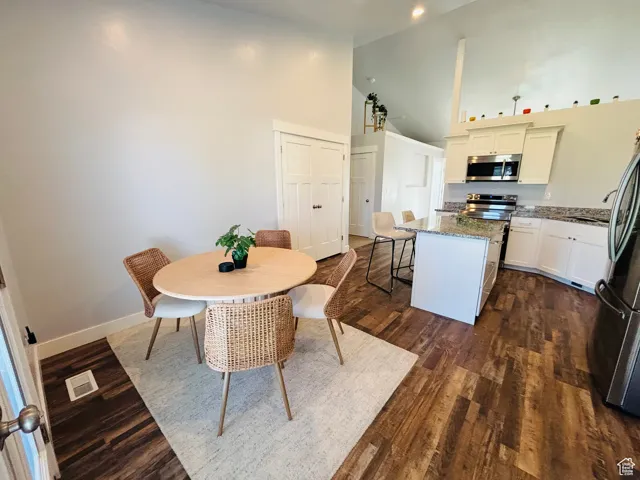 Dining room with high vaulted ceiling and dark wood-type flooring