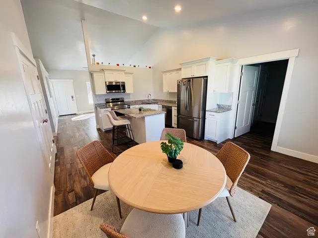 Dining room with dark wood-style floors and high vaulted ceiling
