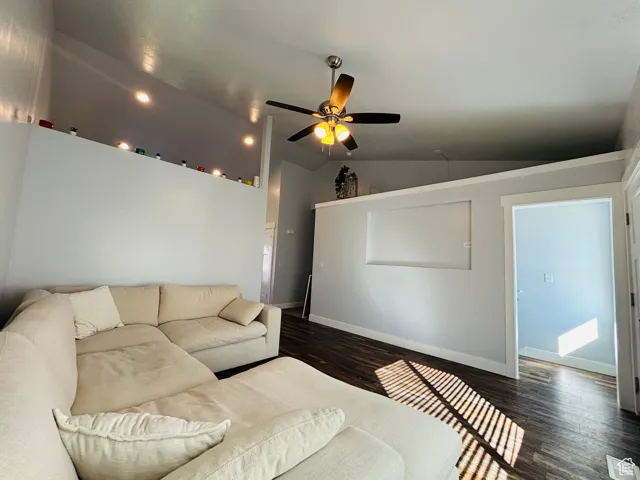 Living room featuring lofted ceiling, wood finished floors, and ceiling fan