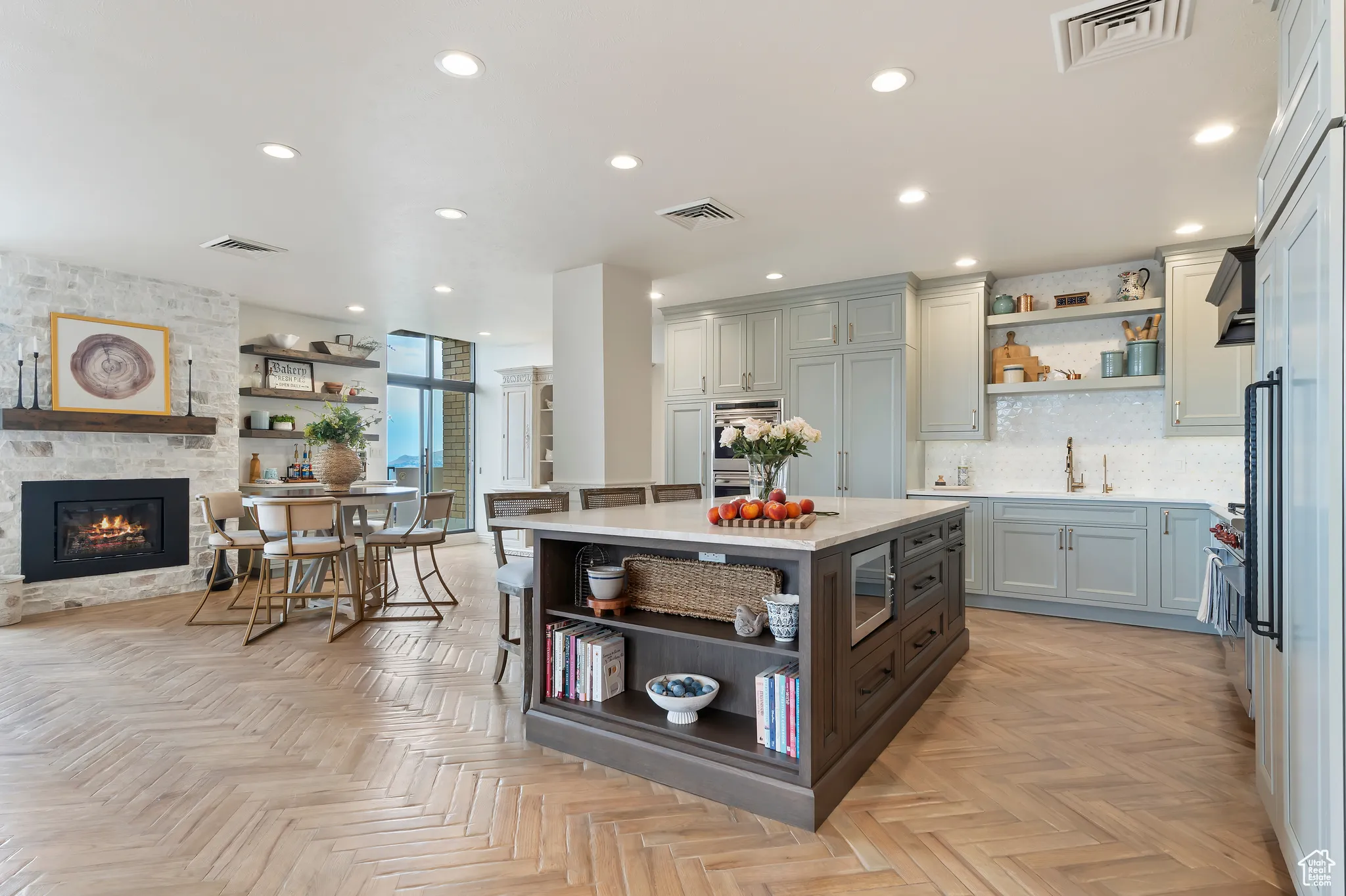 Kitchen with open shelves, light countertops, recessed lighting, a stone fireplace, and decorative backsplash