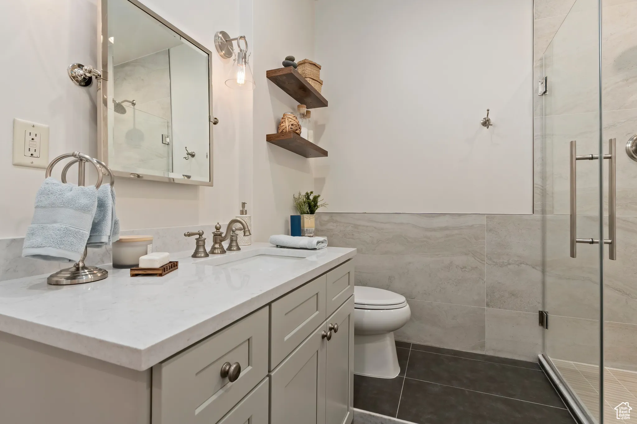 Full bathroom featuring tile walls, vanity, a shower stall, tile patterned floors, and wainscoting