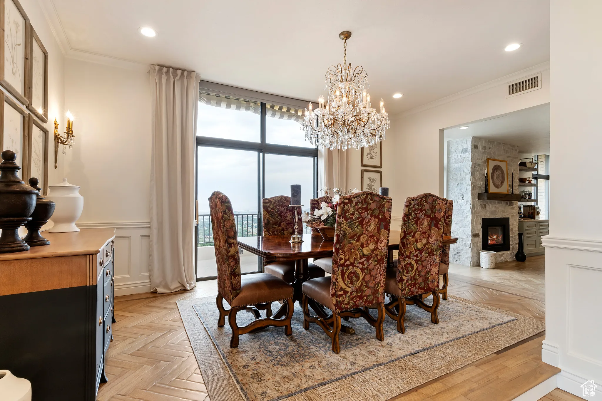 Dining space with ornamental molding, a stone fireplace, a chandelier, wainscoting, and recessed lighting