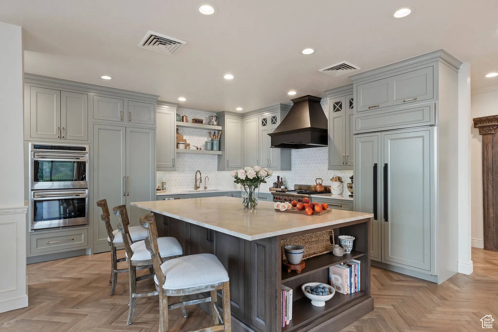 Kitchen featuring open shelves, stainless steel double oven, decorative backsplash, a kitchen bar, and custom range hood