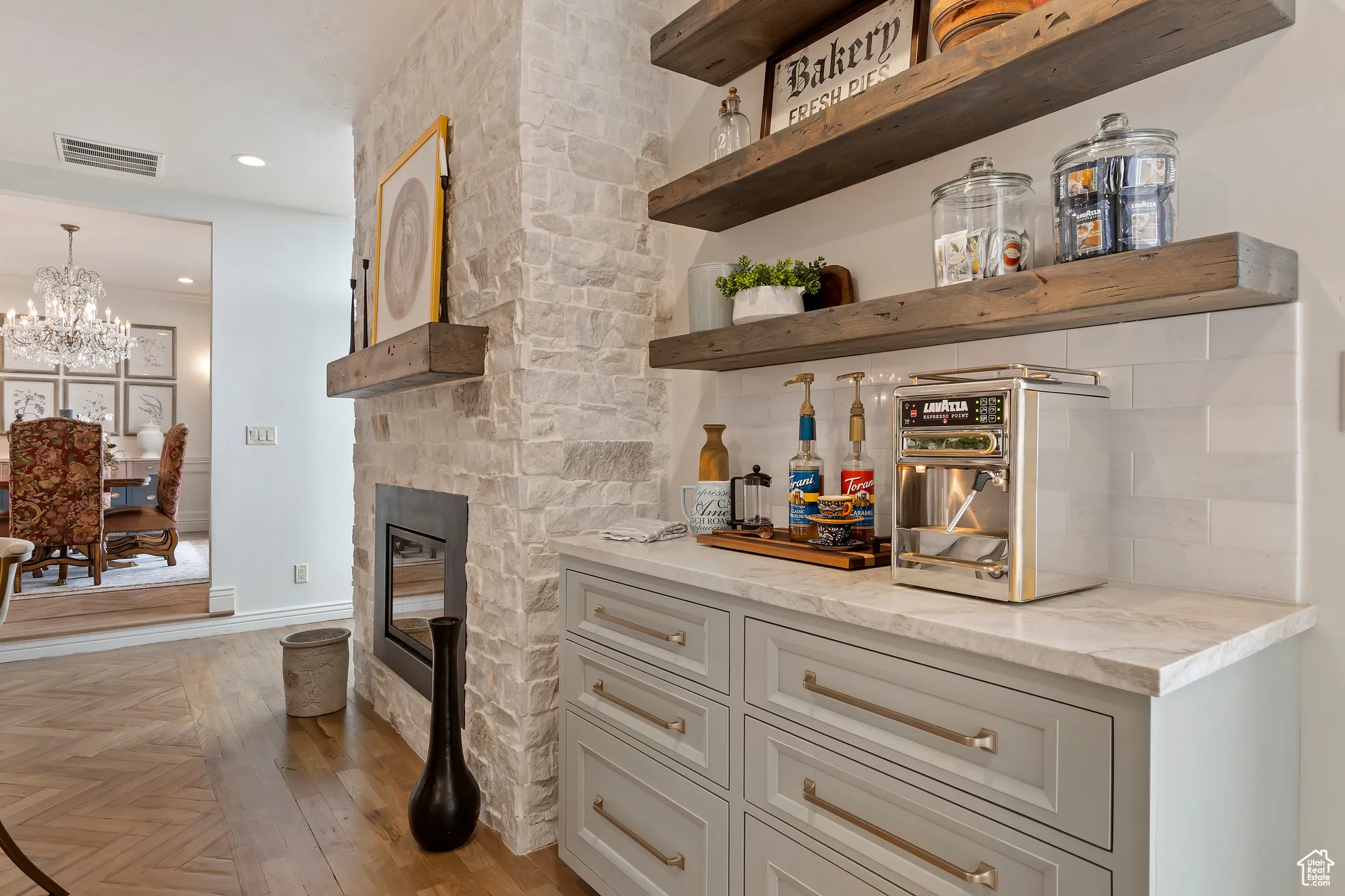 Indoor dry bar featuring a stone fireplace, recessed lighting, light wood-style flooring, a chandelier, and tasteful backsplash