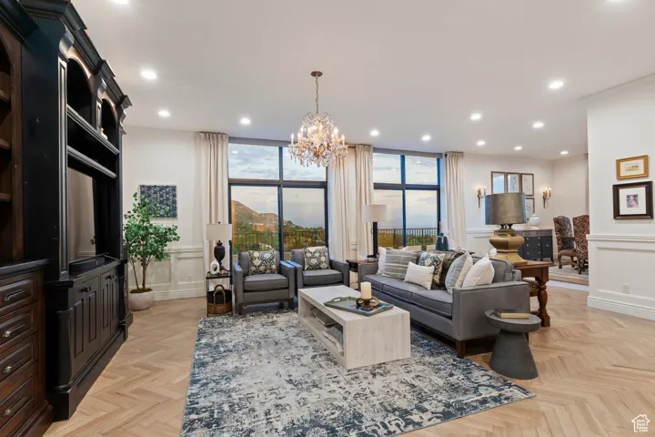 Living room featuring a chandelier, recessed lighting, a wainscoted wall, a decorative wall, and plenty of natural light