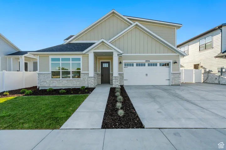 Craftsman-style house featuring stone siding, board and batten siding, driveway, and an attached garage