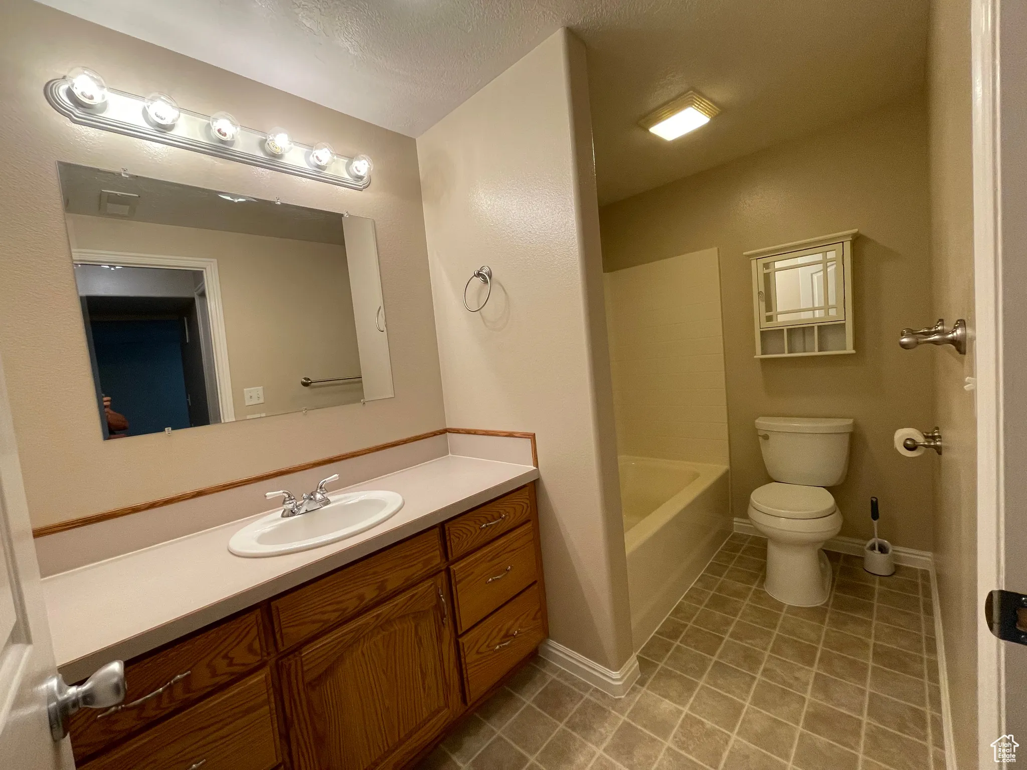 Full bath featuring tile patterned floors, vanity, and a textured ceiling