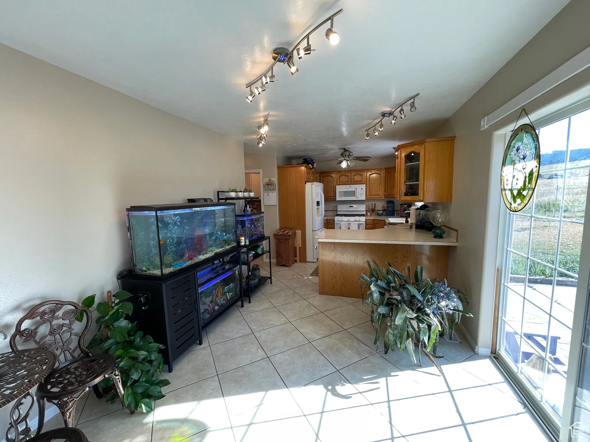 Kitchen with brown cabinets, a peninsula, glass insert cabinets, light tile patterned floors, and white appliances