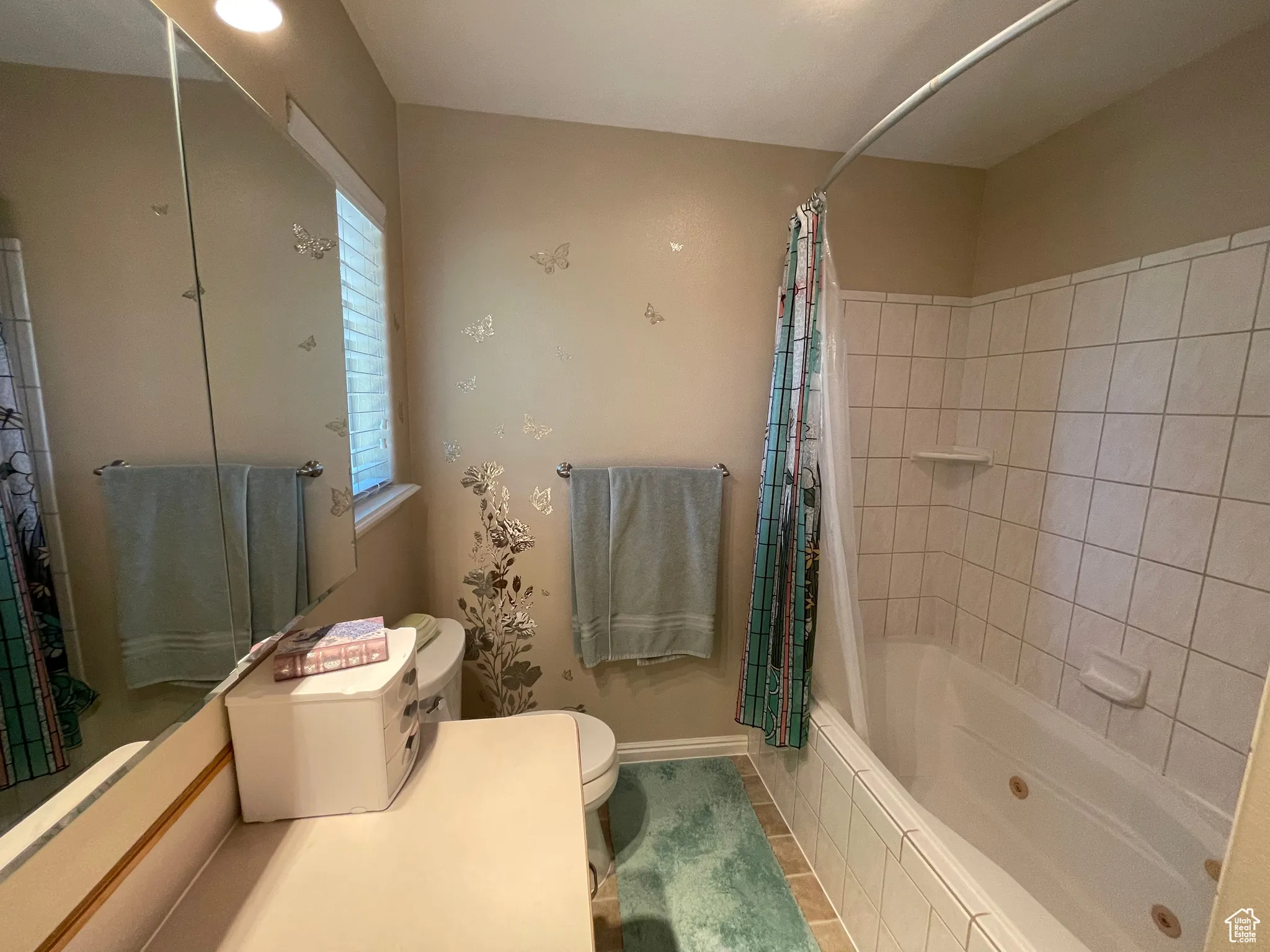 Full bathroom with a combined bath / shower with jetted tub and tile patterned floors