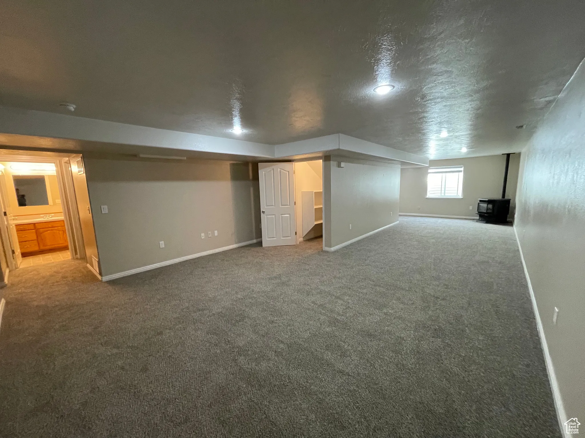 Below grade area featuring a wood stove, carpet floors, and a textured ceiling